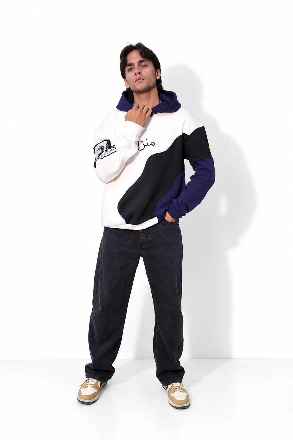 Model wearing the Manzil navy, white and black hoodie with black jeans